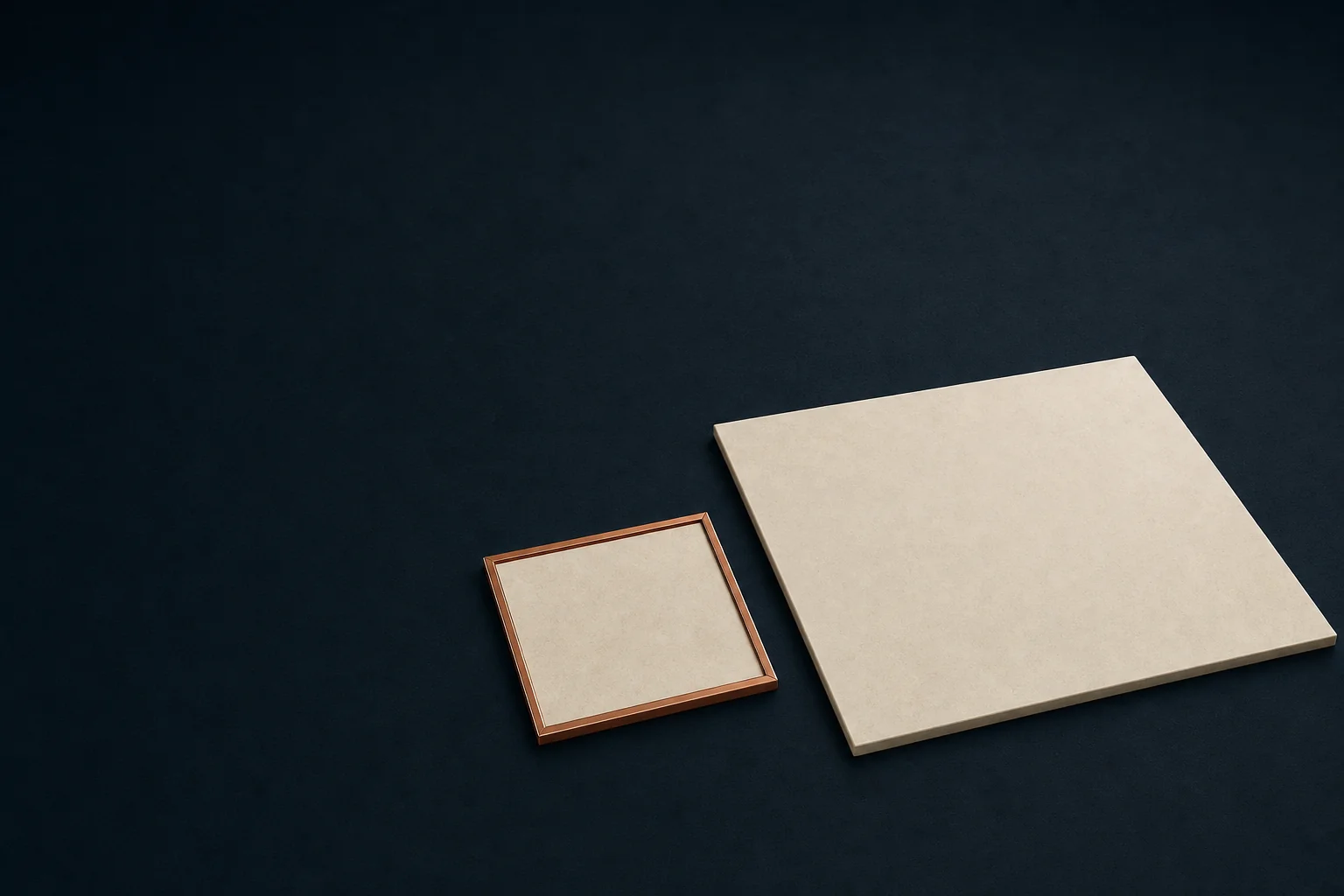 A small ivory pad enclosed by a thin copper frame beside a much larger unframed ivory pad on a dark navy floor